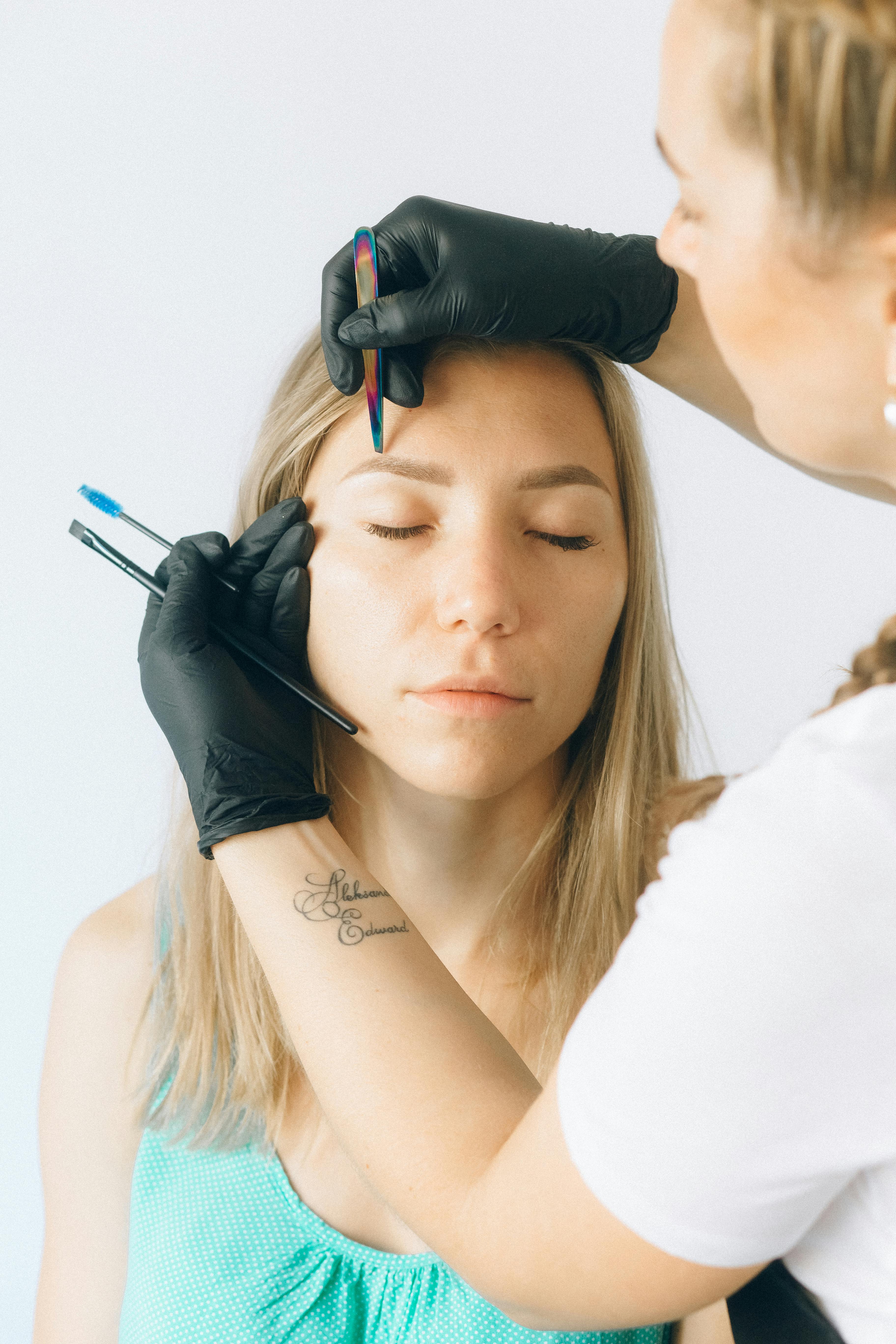 Augenbrauen-Behandlung mit Pinzette und Handschuhen