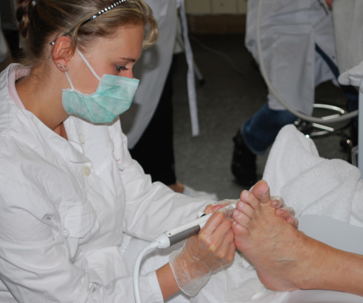 Teilnehmerin der Fußpflege-Ausbildung arbeitet mit der Fräsmaschine