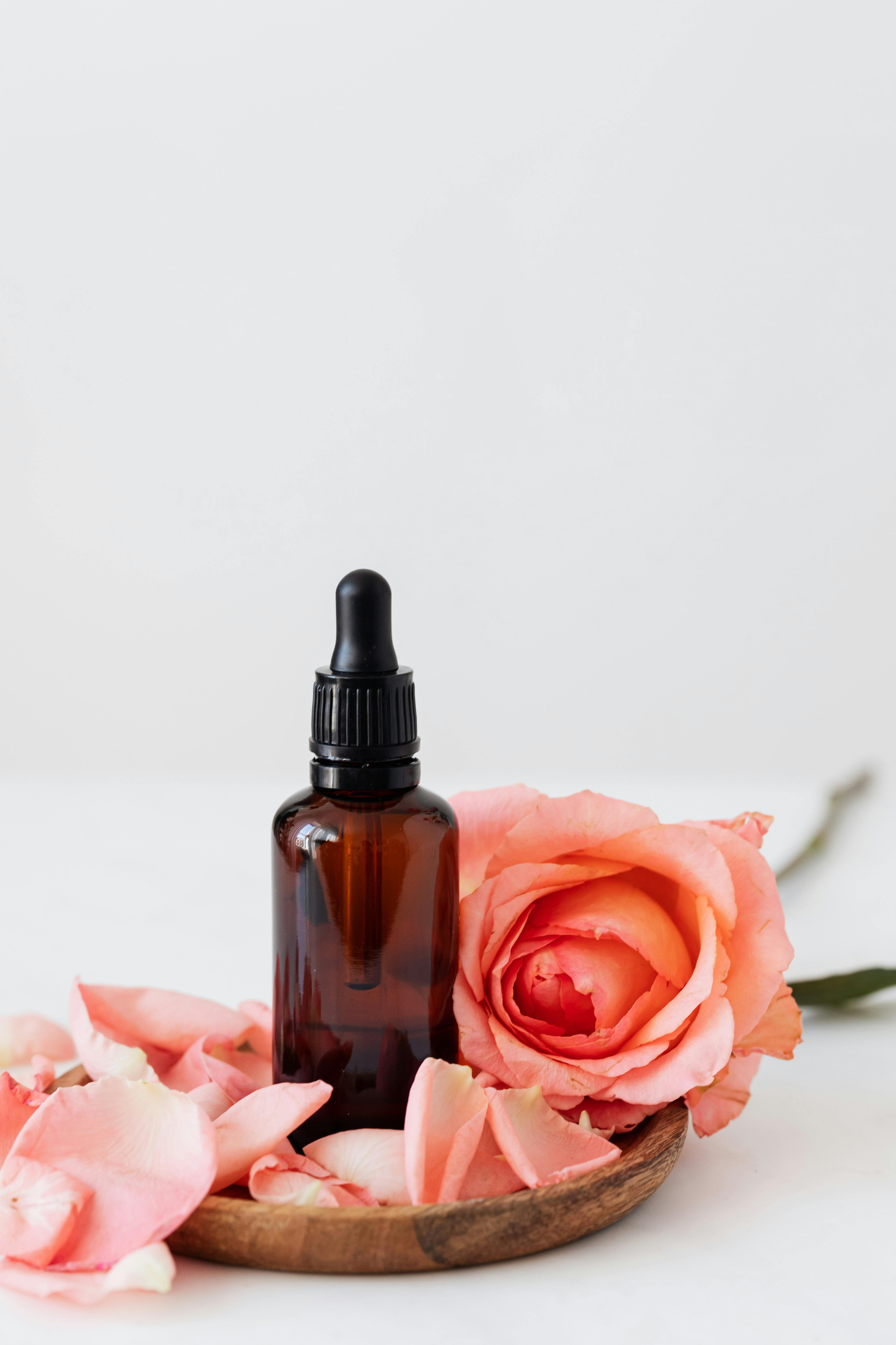 Aromaöl-Fläschchen mit Rosenblüten für die Aromamassage