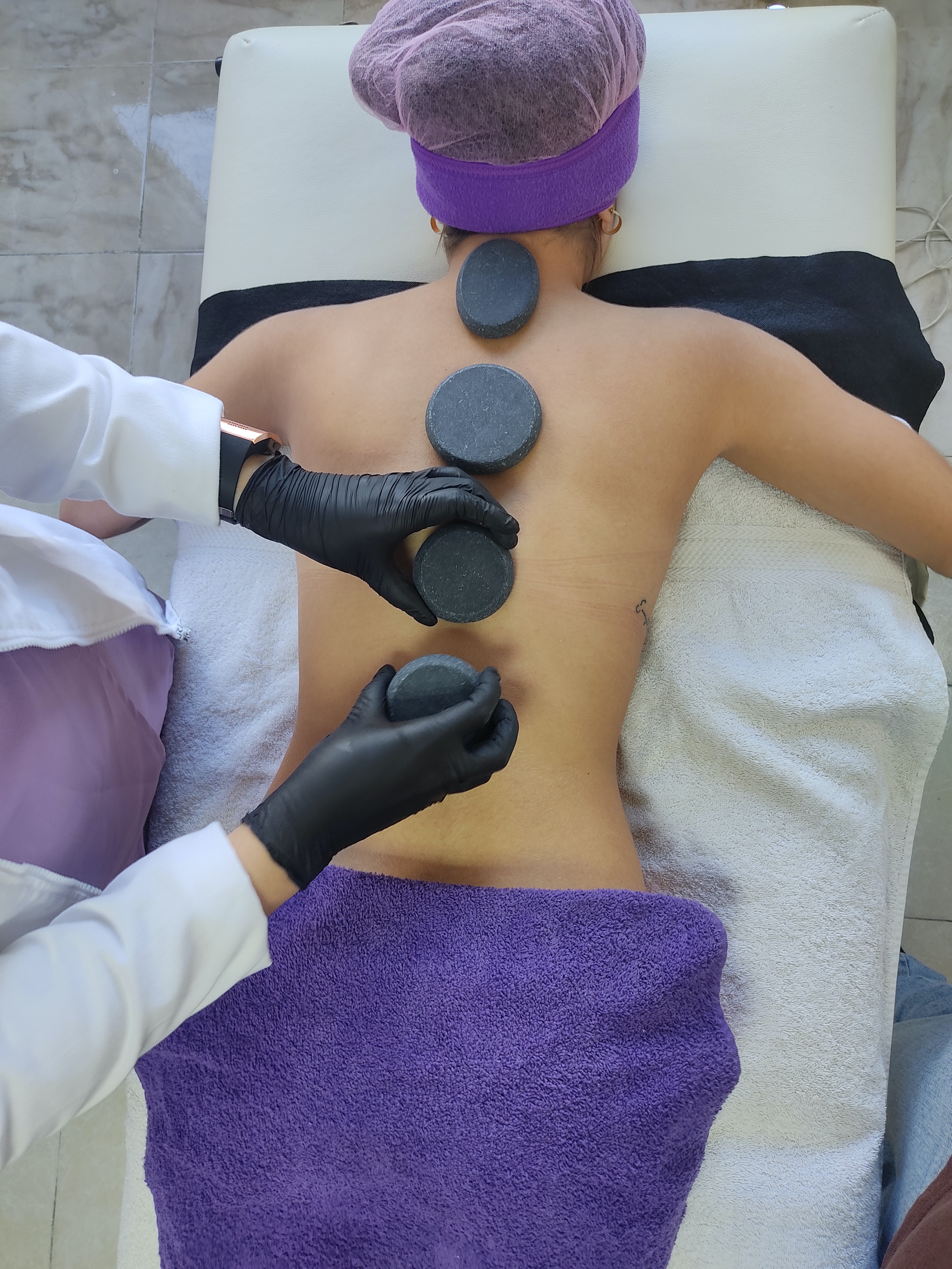 Hot-Stone-Massage mit schwarzen Basaltsteinen auf dem Rücken