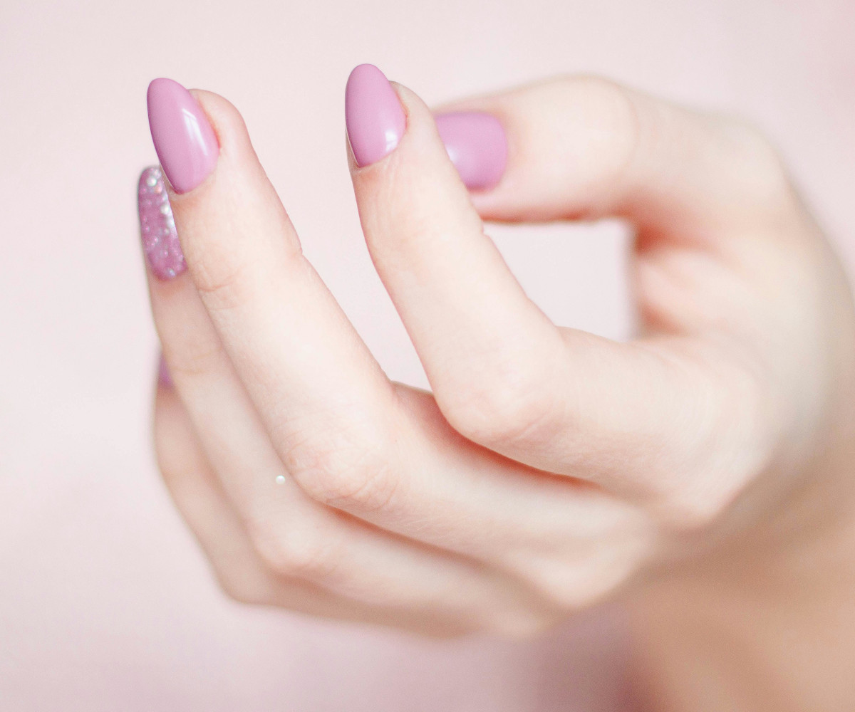 Hand mit rosa lackierten Gelnägeln